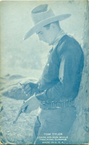 Tom Tyler loads his gun while leaning against a tree blue arcade card